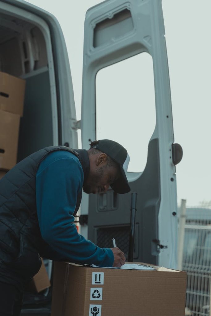 A delivery worker signs documents outside a parked van, managing logistics efficiently.